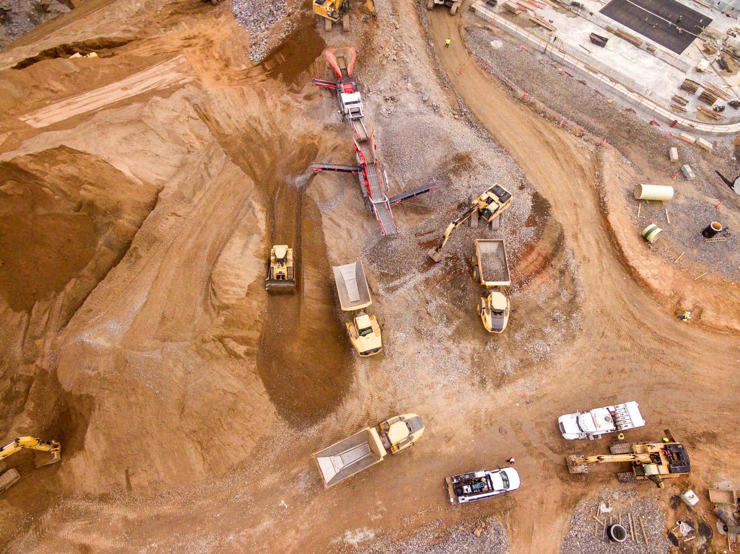Muldenkipper und Baumaschinen auf einer Baustelle, Luftaufnahme
