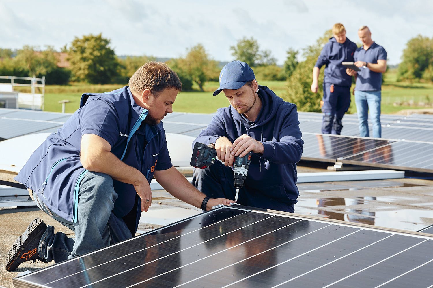 Zwei Monteure von EnergieAktiv montieren gut gelaunt eine Photovoltaikanlage auf einem Flachdach