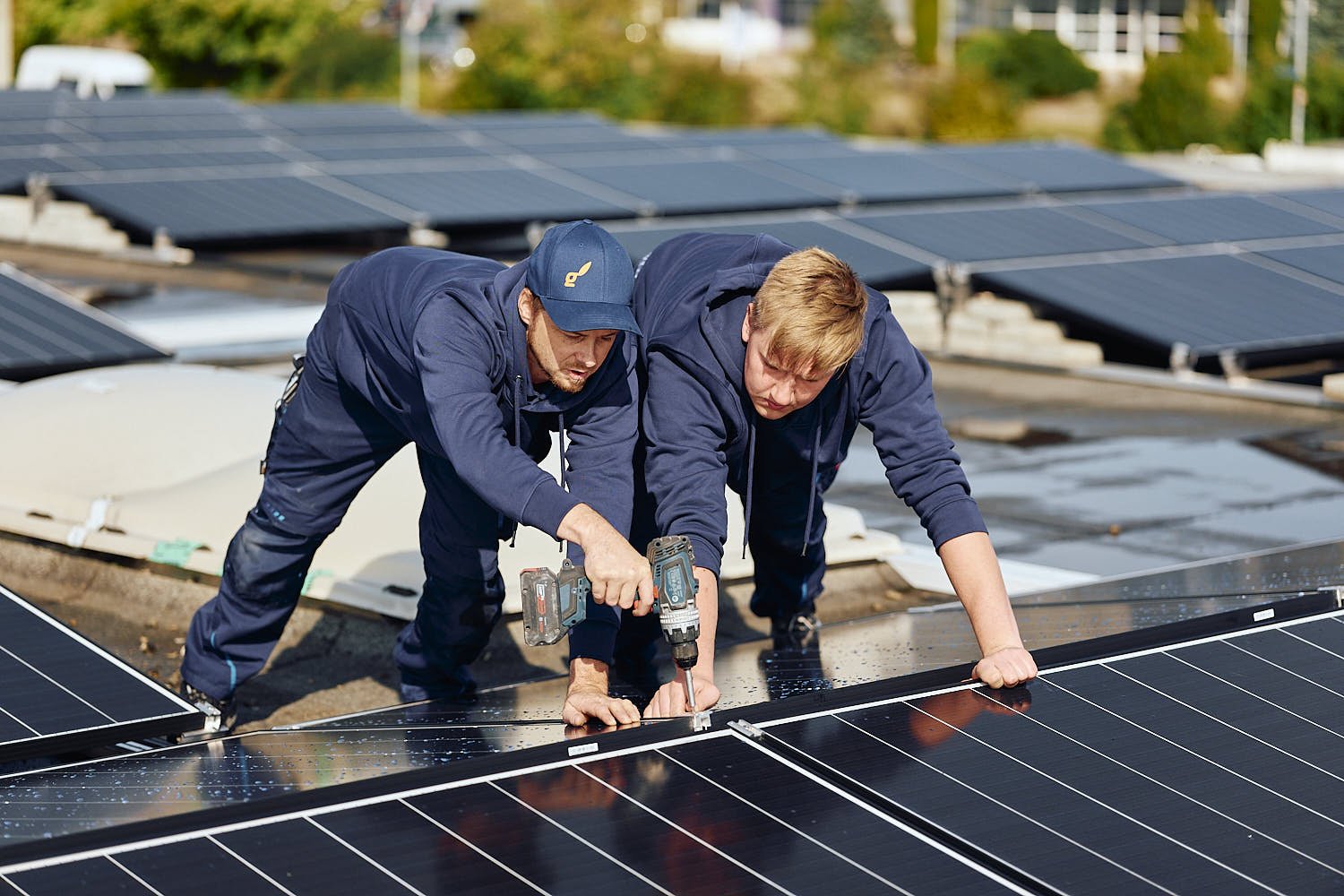 Zwei Monteure von EnergieAktiv verschrauben Photovoltaikmodule auf einem Flachdach